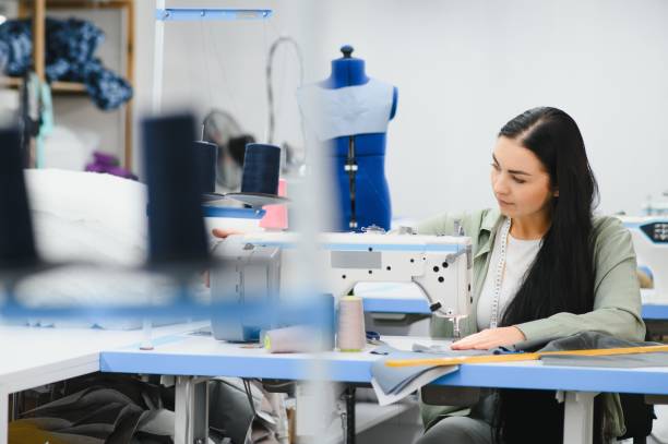 istock Cheerful young seamstress sits at the table with working things, in atelier 1452552870