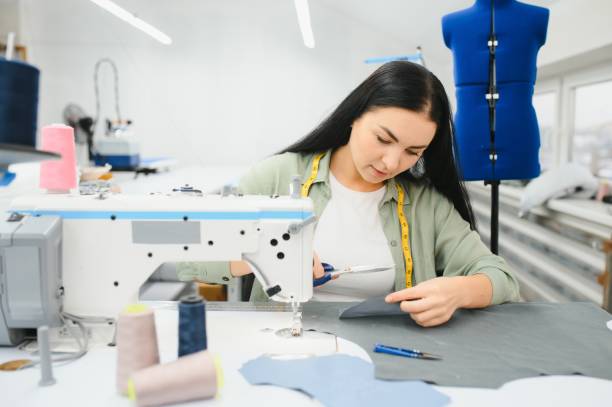 istock Positive young woman sewing with professional machine at workshop. 1452553973