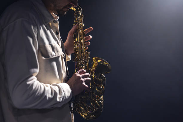 istock Saxophone in the hands of a man on a dark background, copy space. 1452555012