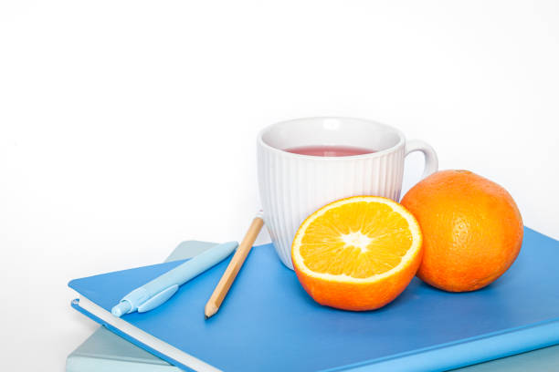 чашка чая, апельсин и блокноты на белом фоне изолированы, копировальное пространство. - stationary pen orange work tool стоковые фото и изображения