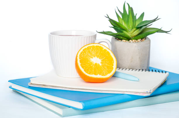 чашка чая, блокноты на белом фоне изолированы, пространство для копирования. - stationary pen orange work tool стоковые фото и изображения