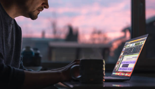 A man works with sound on a laptop early in the morning. stock photo