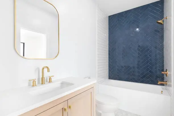 Photo of A bathroom with a natural wood cabinet and blue herringbone tile shower.