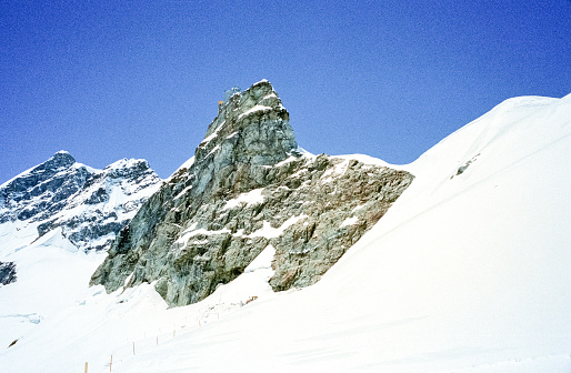 Grindelwald, Switzerland - 1982: A vintage 1980's Nikon negative film scan of the peak of the snow covered Swiss Alps mountains surrounding the small town of Grindelwald, Switzerland.