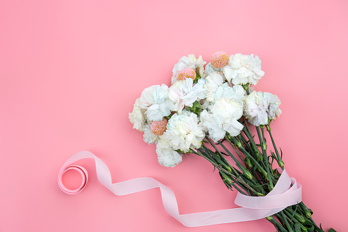 Bouquet of white carnations on a pink background isolated, flat lay, copy space.