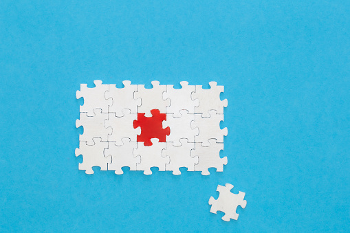 White puzzles and one red on a blue background, flat lay, conceptual minimalism.