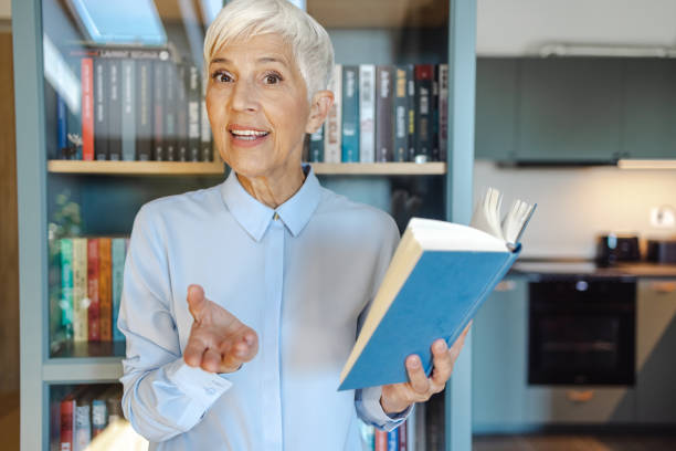 istock Senior female professor holding a book and looking at camera 1452568775