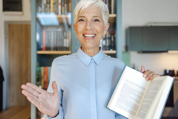 Senior female professor holding a book and looking at camera