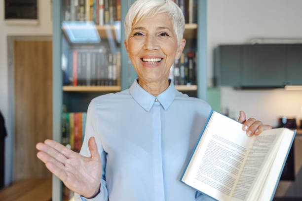 Senior female professor holding a book and looking at camera stock photo