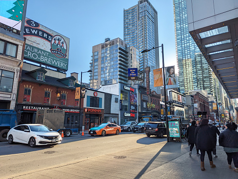 Toronto, Canada - December 8, 2022: Pedestrians walk along the 200-block of Yonge Street just south of Dundas Street West on a cold autumn morning. Popular retailers and entertainment venues line the Garden District of downtown.