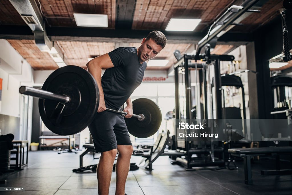 Man weightlifting in gym One man, fit young male exercising with weights in gym. Weight Training Stock Photo