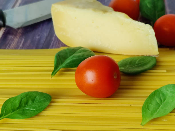 Pasta. Raw spaghetti, cherry tomatoes, spinach leaves and parmesan cheese on a wooden table. Ingredients for cooking pasta bolognese. Close-up