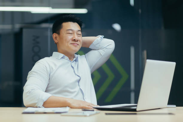istock An man student resting after online study. He is sitting with a laptop, hands behind his head 1452582100