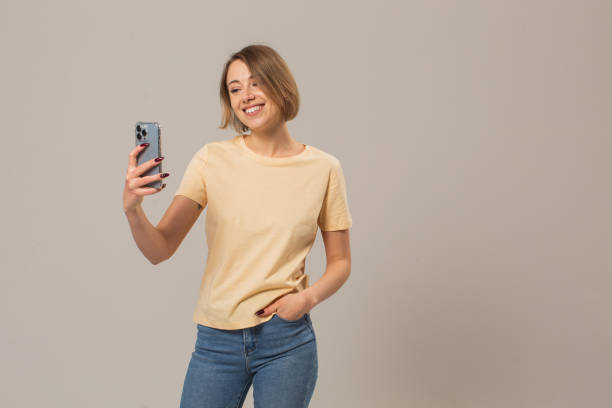 Blonde woman with mobile phone in studio on white background