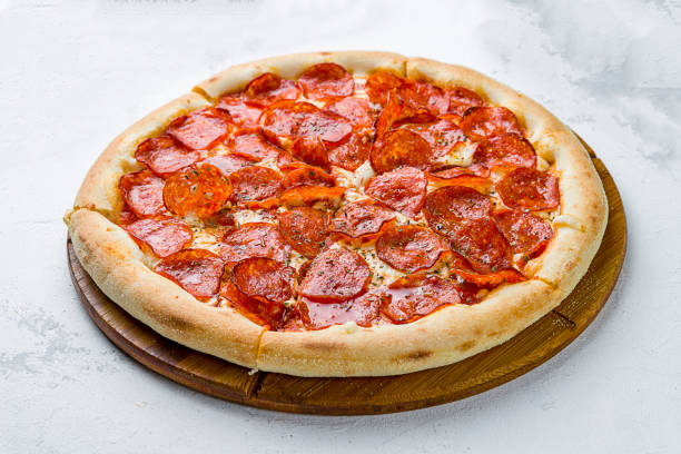 istock Pepperoni pizza on wooden board on concrete table 1452586079