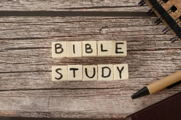 Bible study text word written on wooden cubes with holy bible, pen, and notebook on wooden table. Top view. A close-up.