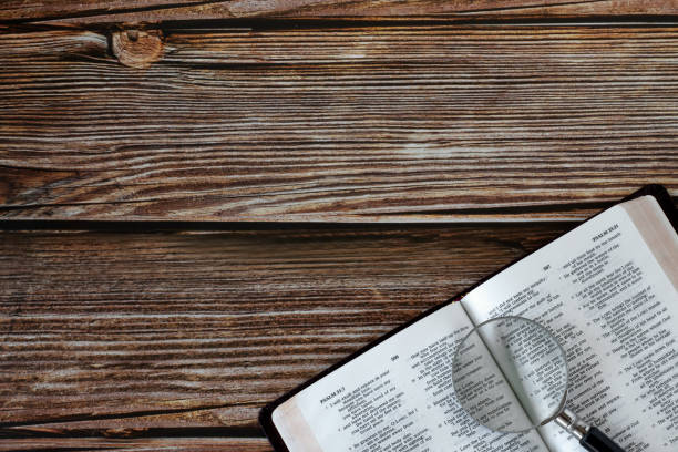 Holy bible book with magnifying glass on wooden table, top view, copy space Holy bible book with magnifying glass on wooden table. Top view. Copy space. Searching, studying, reading Christian Scripures biblical concept. Bible stock pictures, royalty-free photos & images