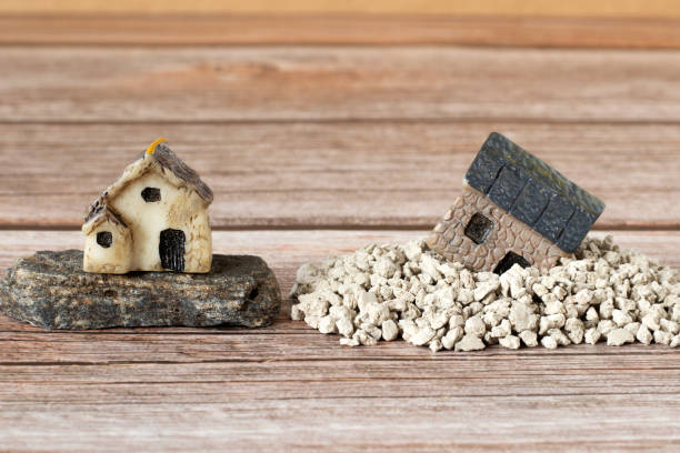 istock Two miniature houses in sand and on rock (stone), copy space for text, a closeup 1452586923