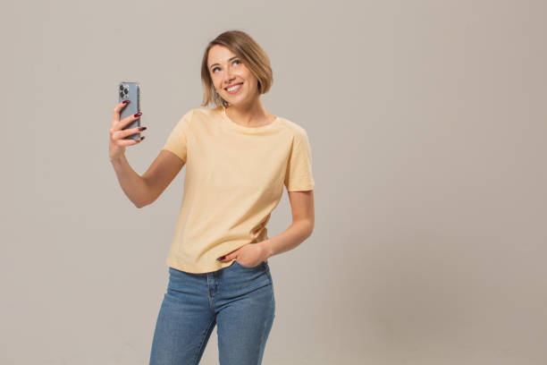 istock Blonde woman with mobile phone in studio on white background 1452587243