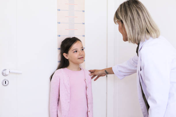 medico nutrizionista femminile che misura l'altezza e il peso di un bambino nel suo studio medico - metro per laltezza foto e immagini stock