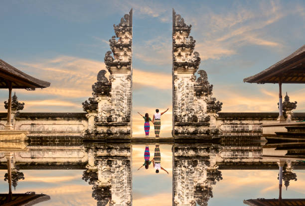 coppia asiatica felice in piedi alle porte del tempio del cielo e tenendosi per mano. perfetta idea per la luna di miele. tempio di lempuyang luhur a bali, indonesia. - bali foto e immagini stock