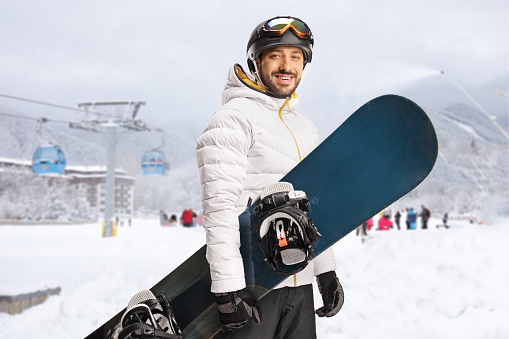 Snowboarder holding a snowboard in front of a cable car