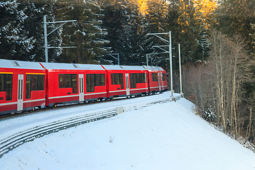 Red passenger train on Rhaetian railway in Canton Graubunden, Switzerland at winter