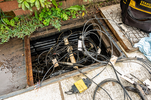 Sydney, Australia - Mar 9, 2022: Opened manhole on a street for underground cable repair works. Configuration of wiring for residential broadband internet access.