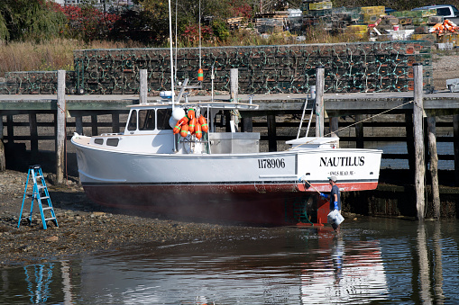 Owls Head, USA - October 14, 2021. A man painting fishing boat at Owls Head, Maine, USA