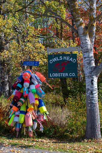 Owls Head, USA - October 14, 2021. Road sign decorated with lobster buoys at Owls Head, Maine, USA