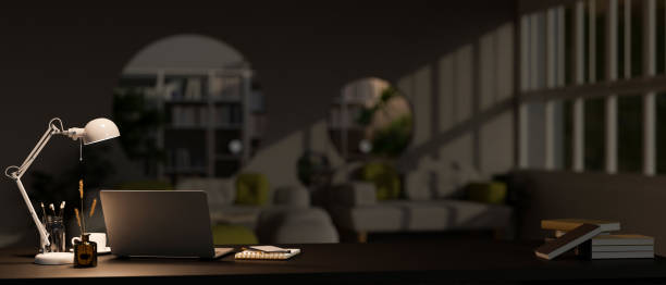istock Modern home office at night with laptop, light from table lamp, and accessories on table 1452607676