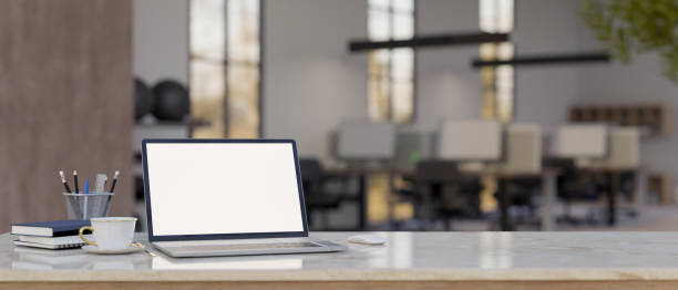 istock Modern bright office desk with laptop mockup and copy space over blurred office in the background 1452607677