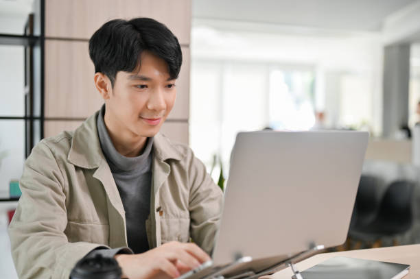 istock Handsome Asian male office worker or developer working on his task on laptop in the office. 1452611431