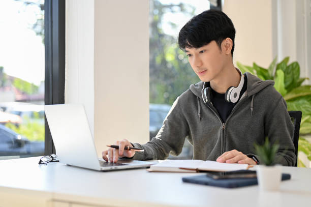 istock Smart young Asian male college student doing his school homework 1452611444