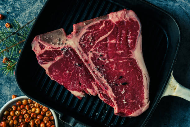 istock Thick Raw T-Bone or porterhouse Steak in a grill pan with peppers 1452611571