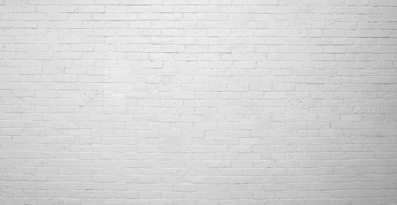 The painted (white) brick wall of the building. White brick wall construction background, rough surface.