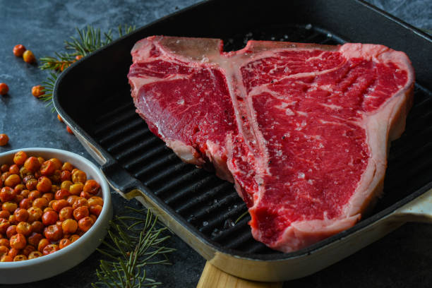 istock Thick Raw T-Bone or porterhouse Steak in a grill pan with peppers 1452611614