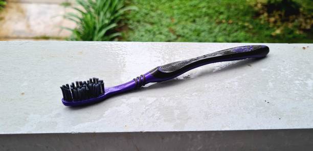 cepillo de dientes negro en la pared gris - dental hygiene elegance black toothbrush fotografías e imágenes de stock