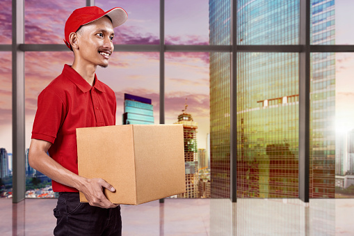Parcel delivery man with a hat carrying a package in the city