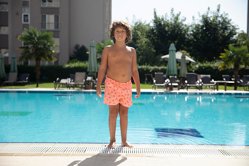 Portrait of smiling little boy enjoying underwater swim in the pool. The boy is gliding by the camera during swimming lesson. Sunny summer day.