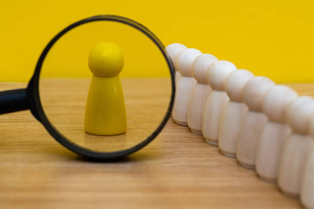 Magnifying glass looking at wooden figurine stock photo