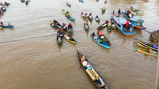 Banjarmasin, Kalimantan - Indonesia – 30 October 2022: everyday in the morning, women in floating market lok baintan, Banjarmasin city, Indonesia paddled their boat to carry out buying and selling various basic needs such as vegetables and crops from villages along martapura river.