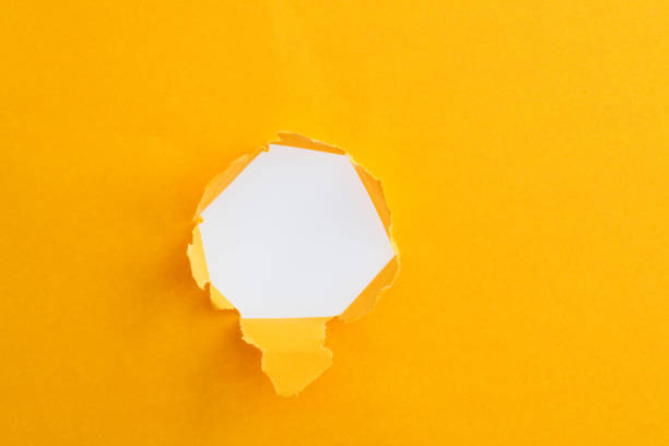 желтая бумага с круглым отверстием - hole punched paper стоковые фото и изображения