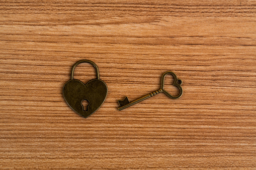 Heart shaped key and lock on wooden table.