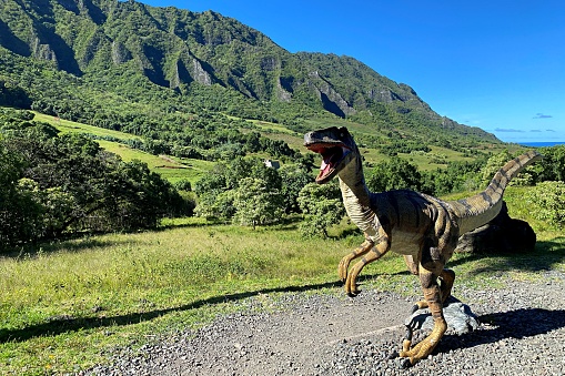 A dinosaur model standing against the backdrop of a vast meadow