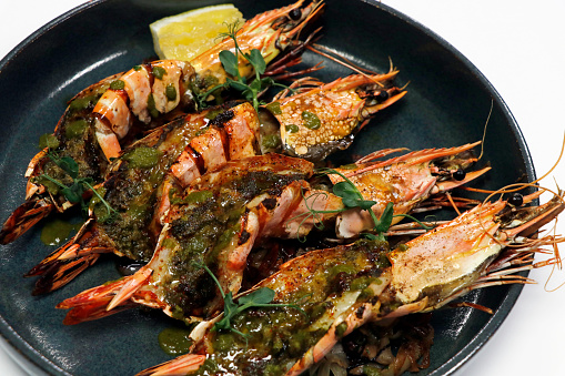 mediterranean style marinated grilled king tiger prawns or shrimps in a plate with white background