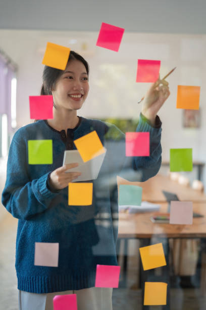 istock Confident businesswoman planning while looking at adhesive notes stuck on a glass wall. 1452631389
