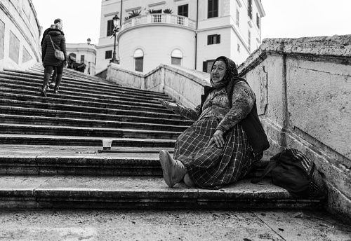 Rome, Italy - December 22, 2022: A beggar asking for some changes on the Spanish Steps during Christmas shopping season in Rome, Italy