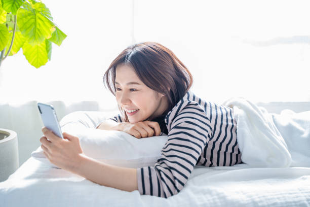 istock Smiling woman looking at smartphone screen in bed. 1452643300