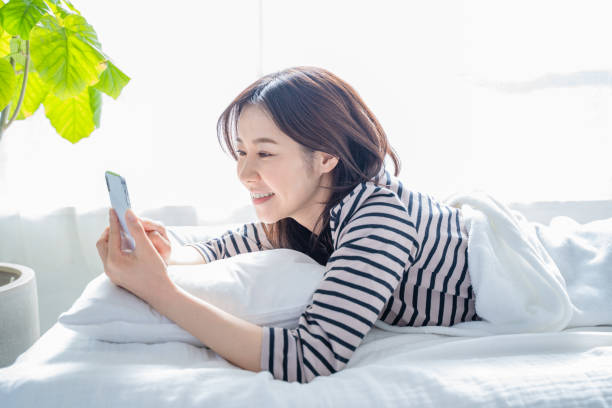 istock Smiling woman looking at smartphone screen in bed. 1452643301